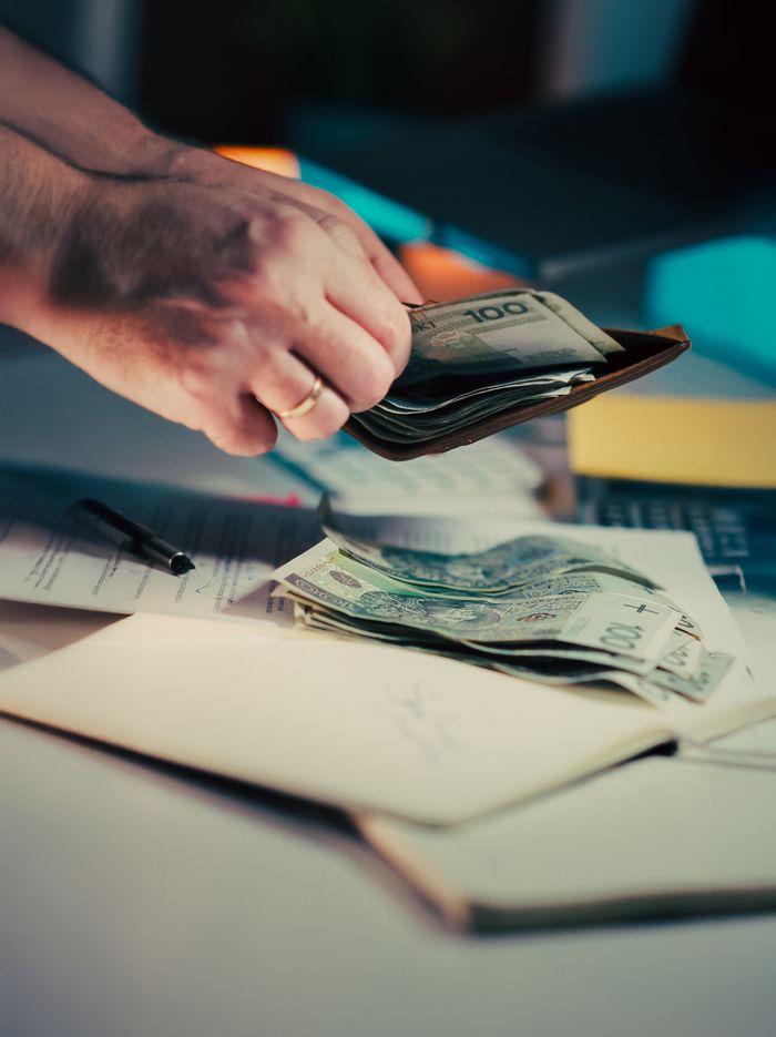 A person manages currency and documents on a desk, illustrating finance and budgeting.