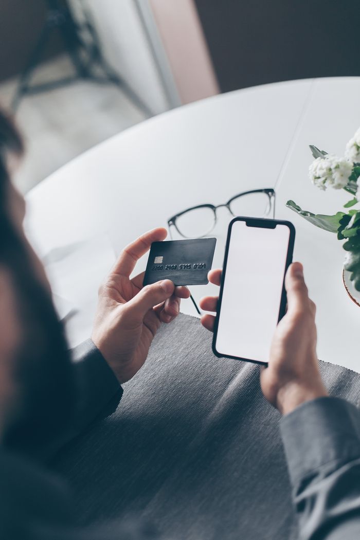 Man using a credit card and smartphone, ideal for banking and technology themes.